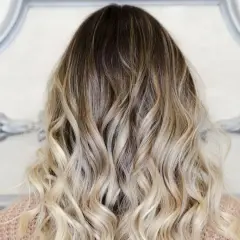 Piękne ombre włosy, od ciemnego brązu po jasny blond, delikatnie pofalowane.
