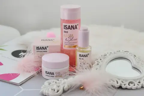 Zestaw kosmetyków Isana Glow & Shine: krem, olejek i tonik. Różowe piórka i lusterko dodają uroku.