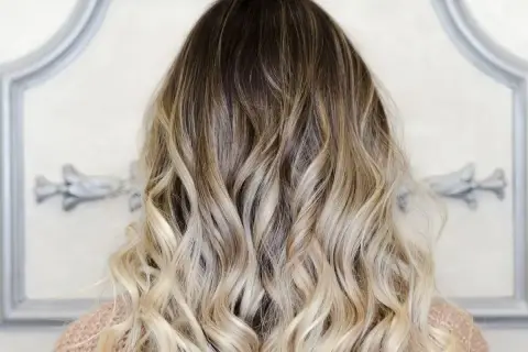 Piękne ombre włosy, od ciemnego brązu po jasny blond, delikatnie pofalowane.
