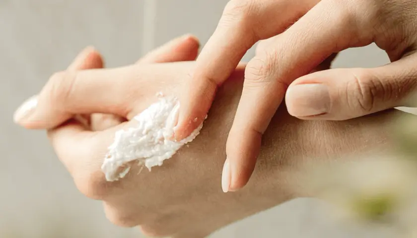 Delikatny peeling do rąk rozprowadzany palcami, z widocznym zadbanym paznokciem.