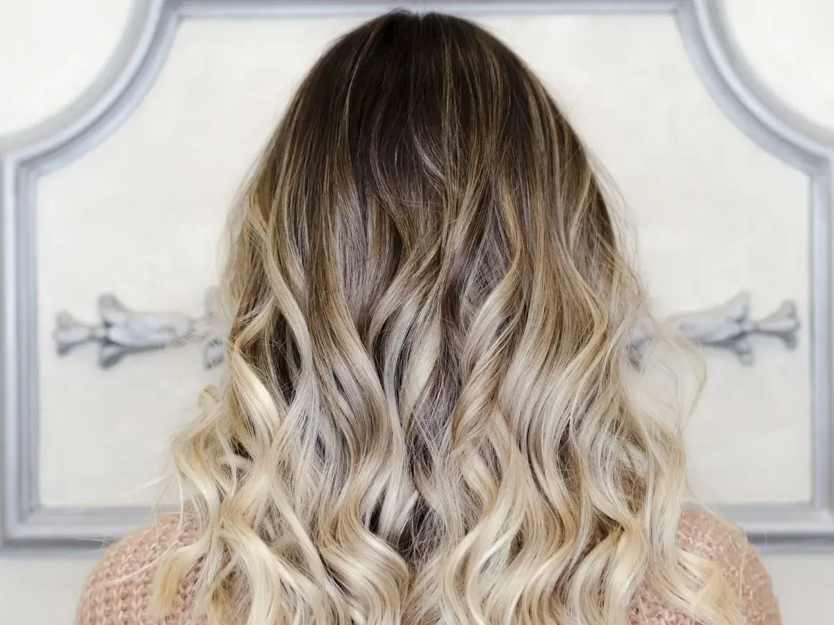 Piękne ombre włosy, od ciemnego brązu po jasny blond, delikatnie pofalowane.